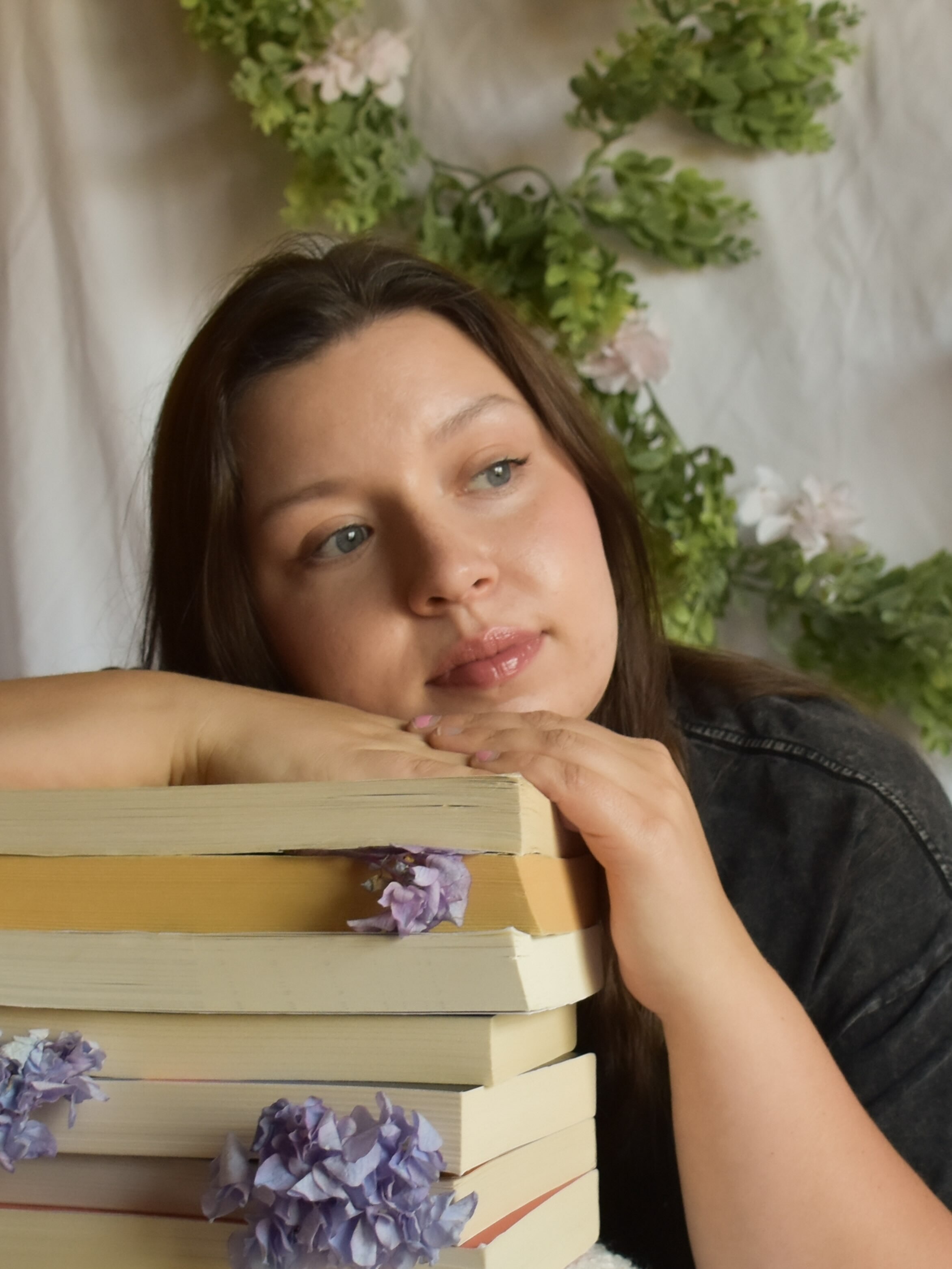Amber resting beside a stack of books decorated with purple flowers