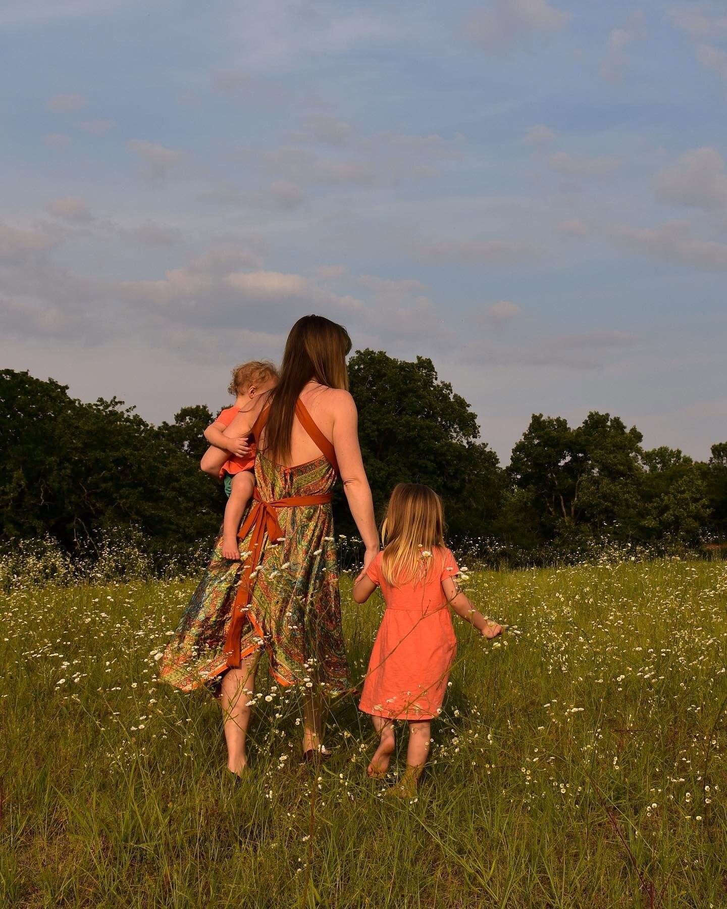 Mother walking through a wildflower field with her two young children