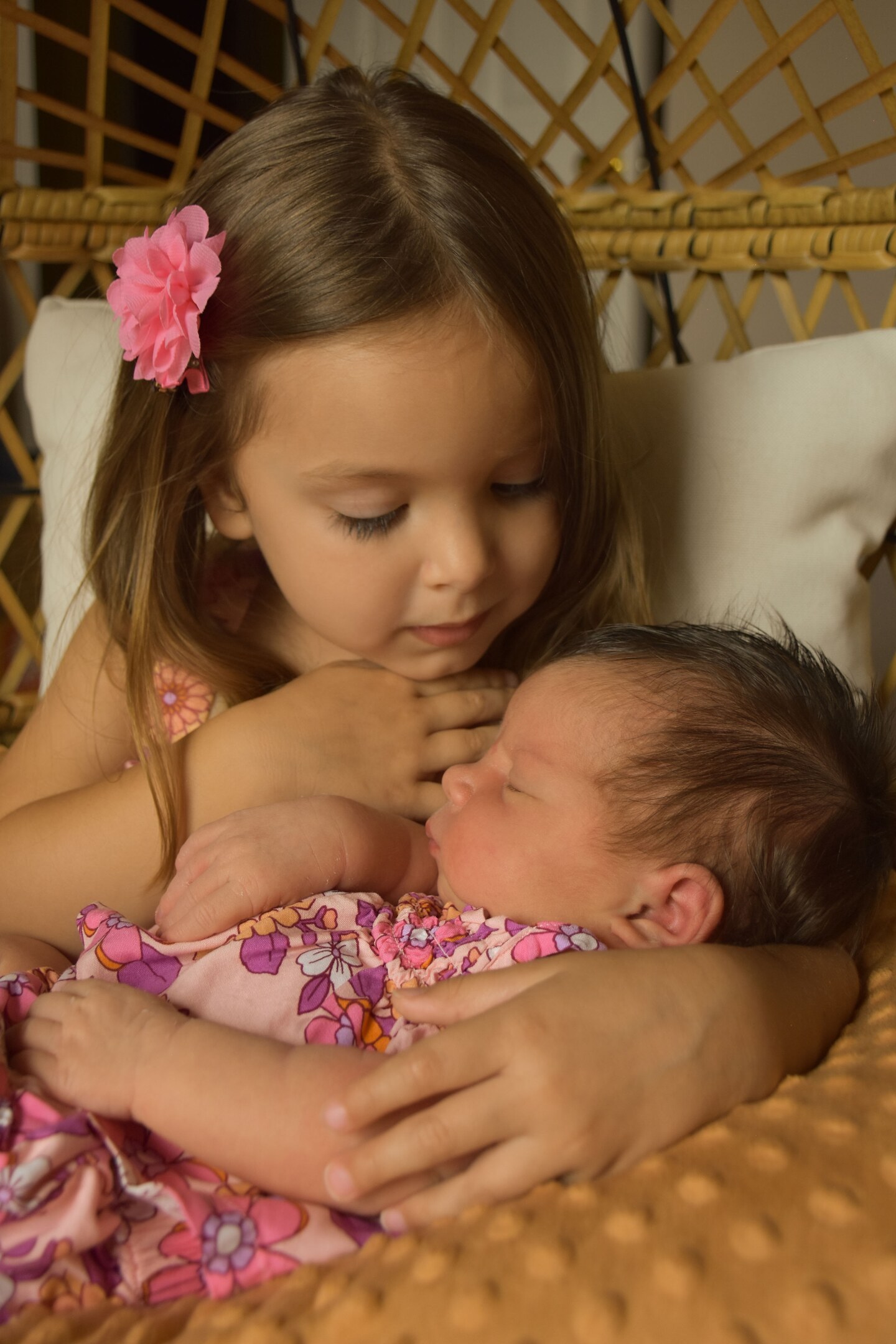 Young girl cradling her sleeping newborn sister