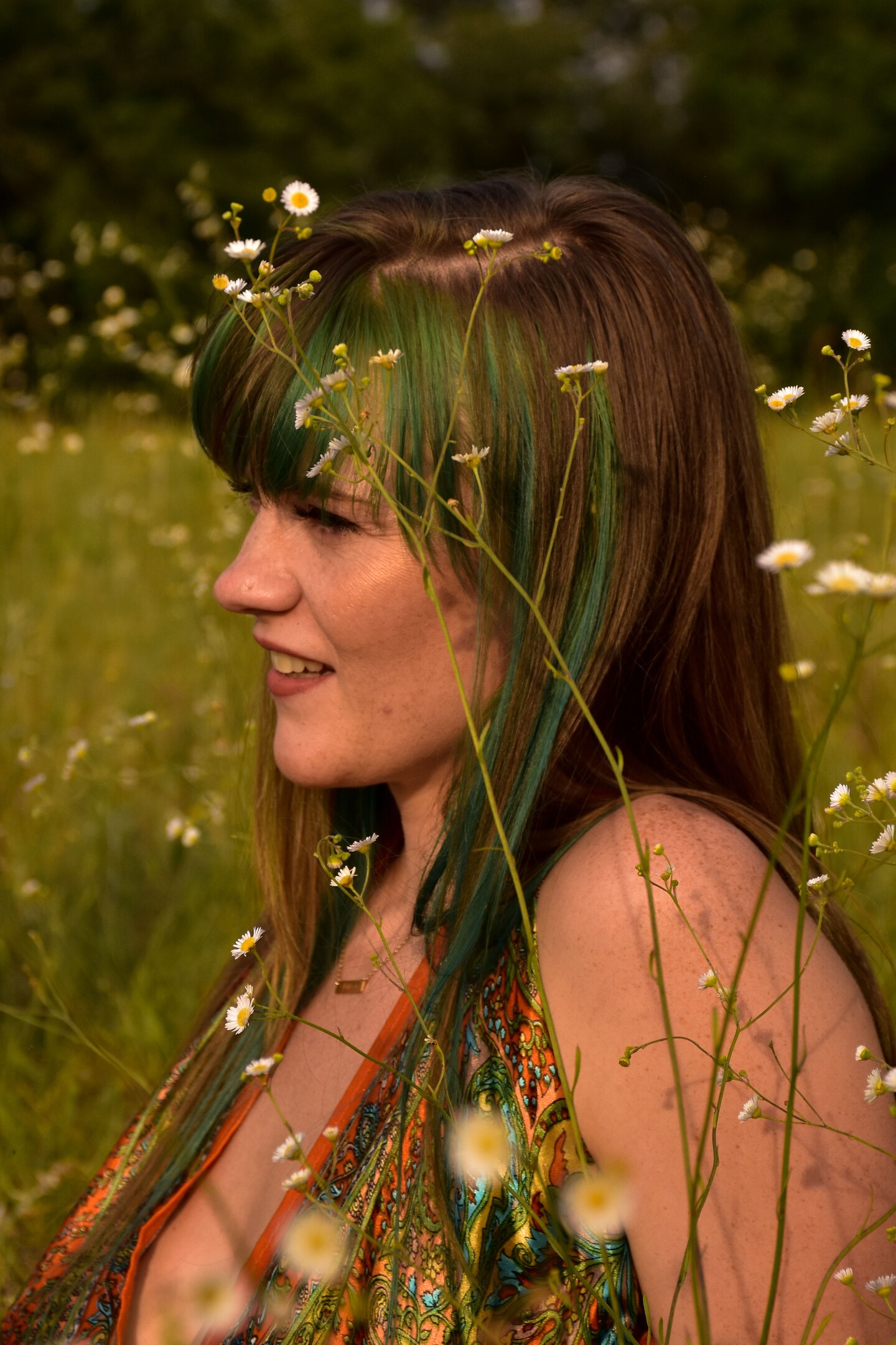Woman with teal-streaked hair surrounded by wildflowers